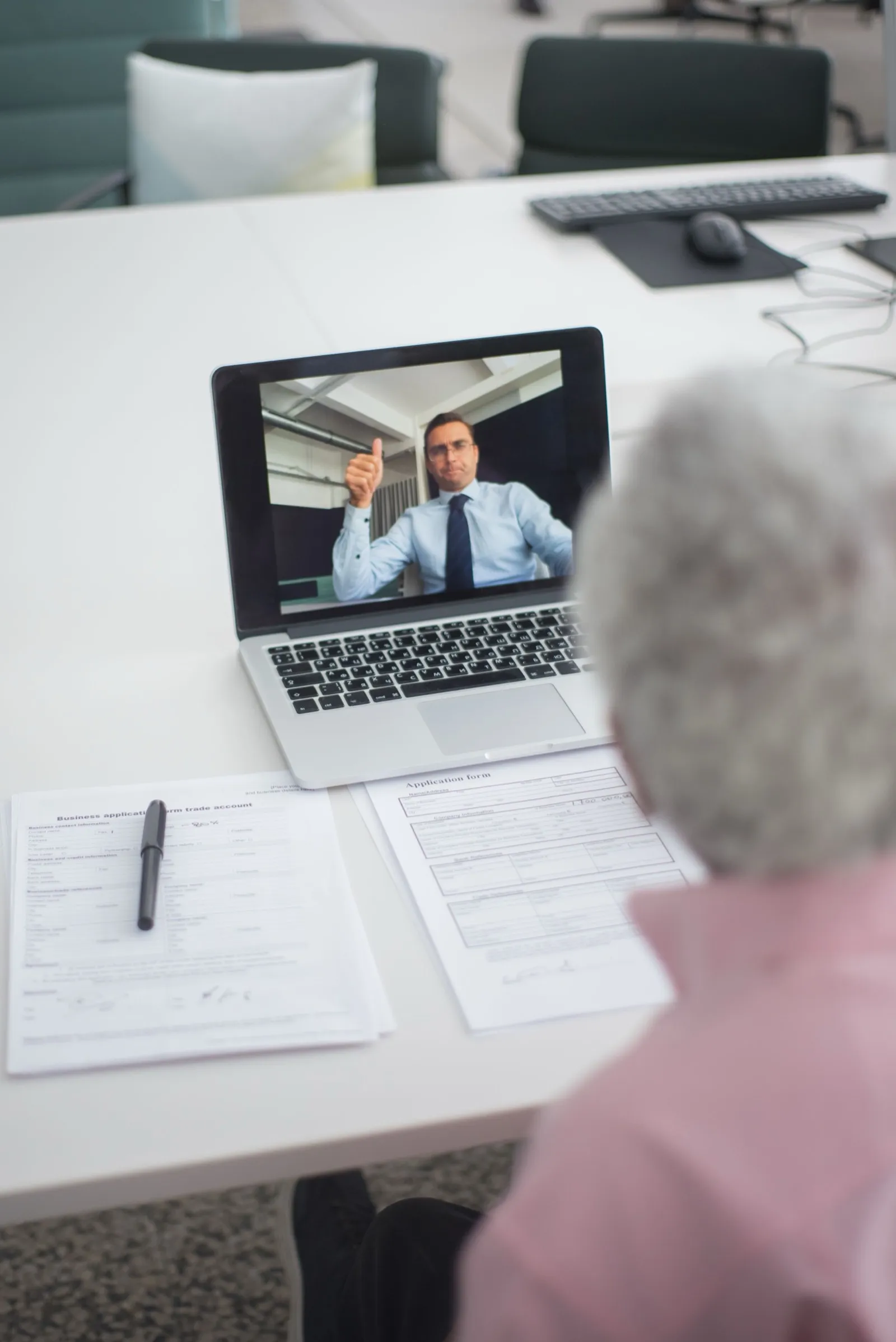 A video call participant giving a thumbs up on screen